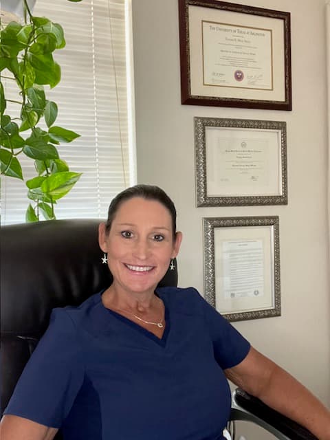 Tascha sitting and smiling with credentials behind her.